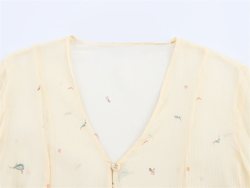 Light yellow cardigan with small colorful patterns on a white background