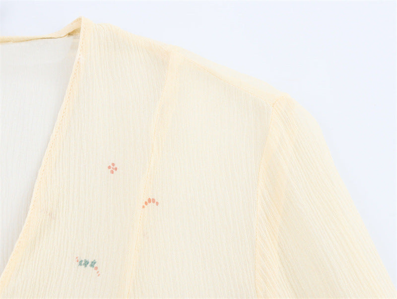 Light yellow fabric with embroidered designs on a white background