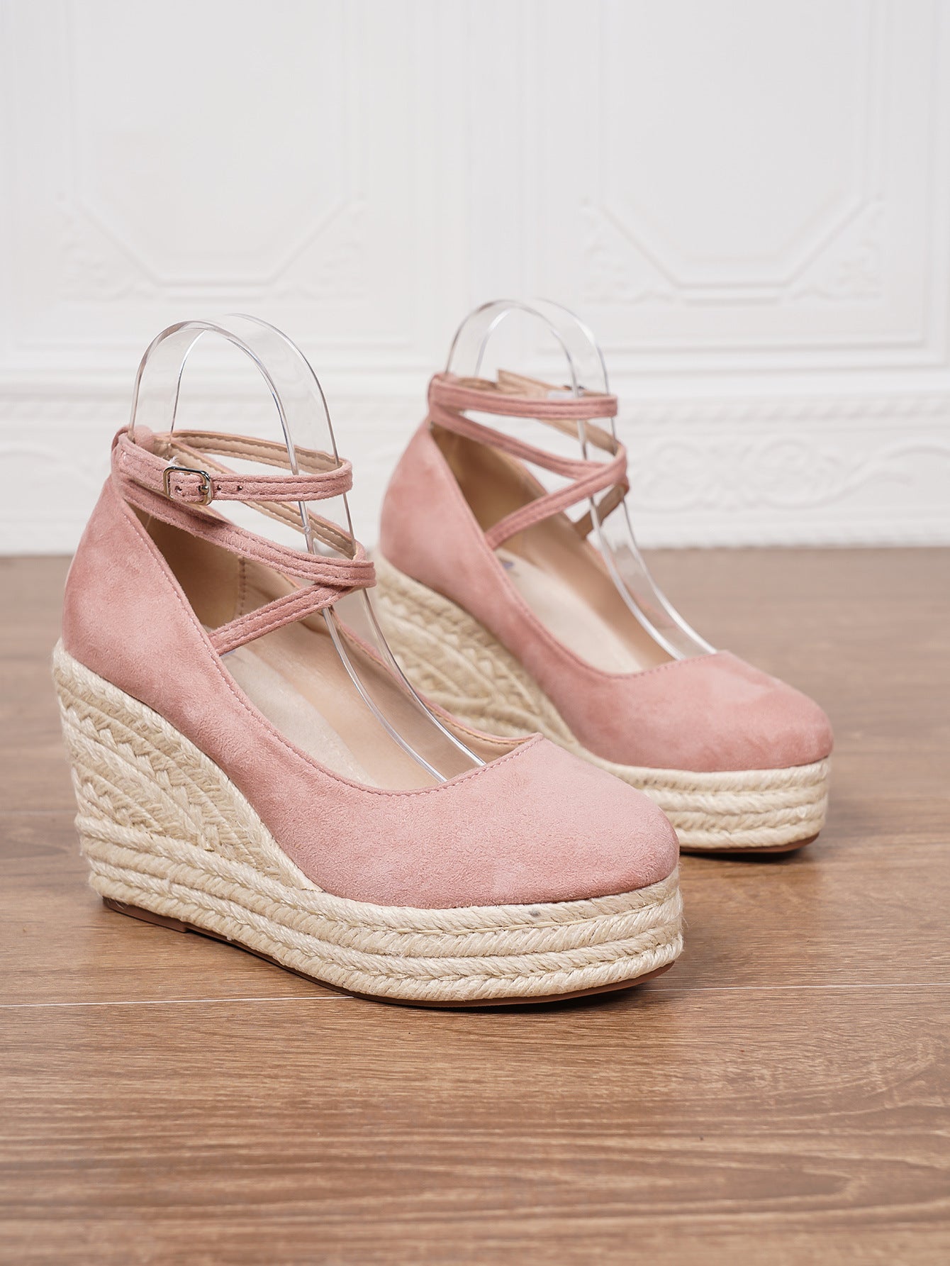 Pink wedge sandals with espadrille soles on a wooden surface