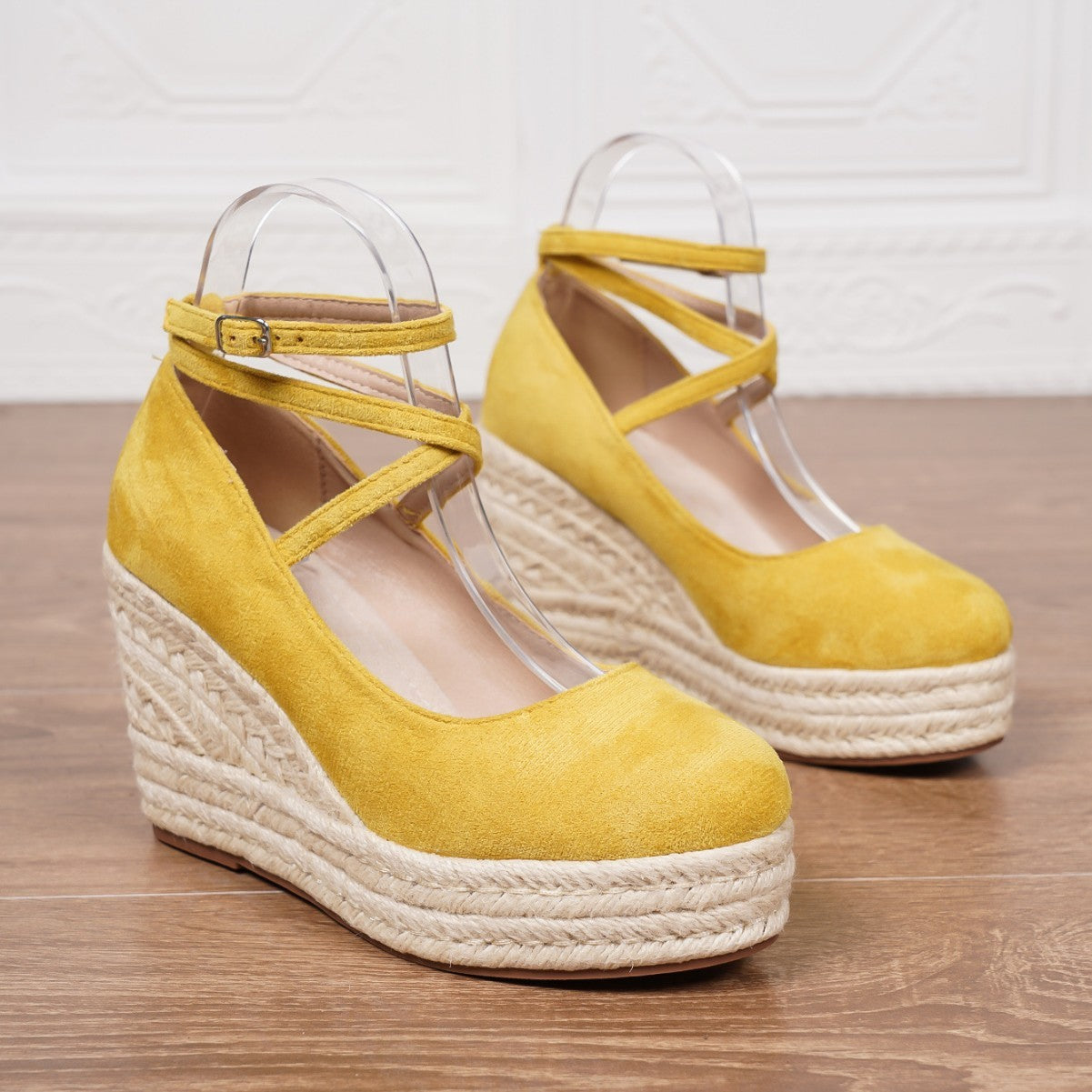 Yellow wedge sandals with espadrille sole on a wooden surface