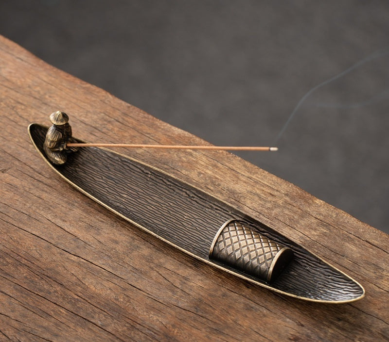 Bronze fisherman fishing line incense holder on a wooden surface with incense sticks.