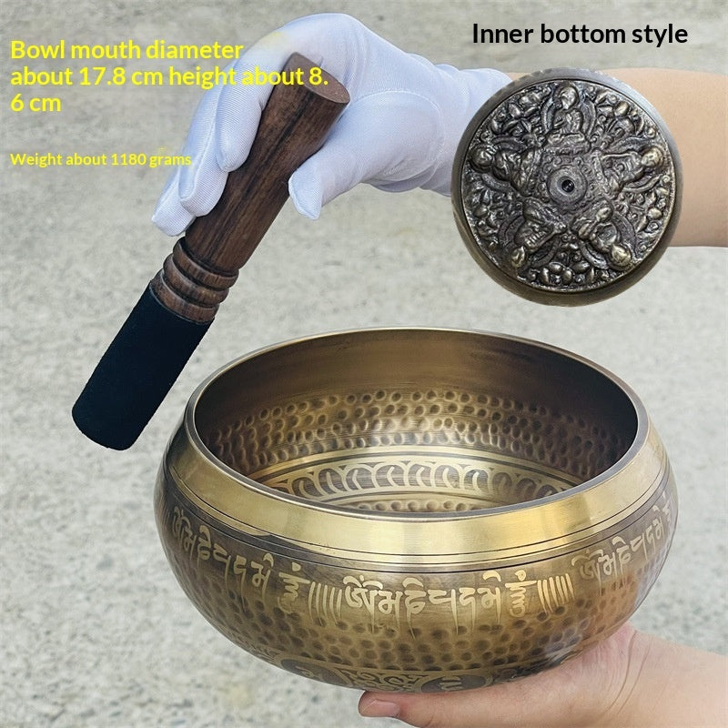 Bronze singing bowl with wooden striker and white gloves on a neutral background
