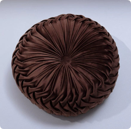 Brown round pillow with pleated texture on a white background