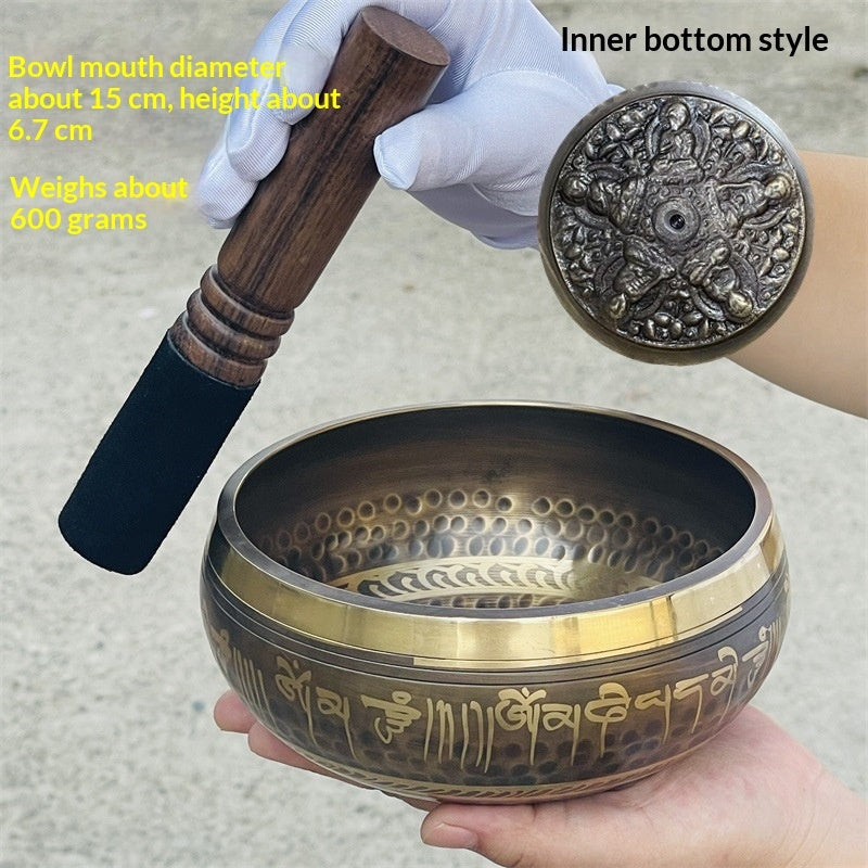 Tibetan singing bowl with wooden mallet and decorative cover on a neutral background