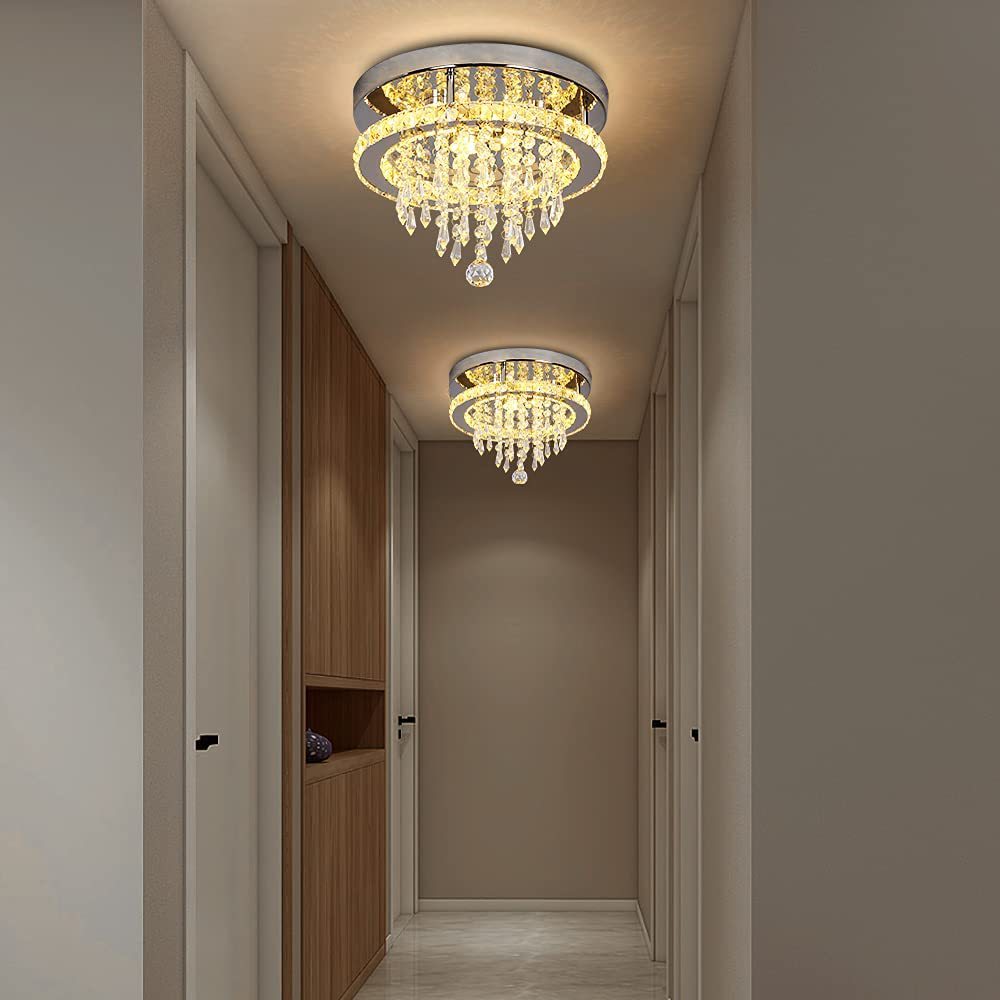 Chandelier lighting fixtures in a hallway with neutral walls and wooden cabinet.