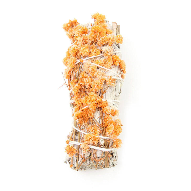 Clear glass vase filled with orange flowers and branches on a white background