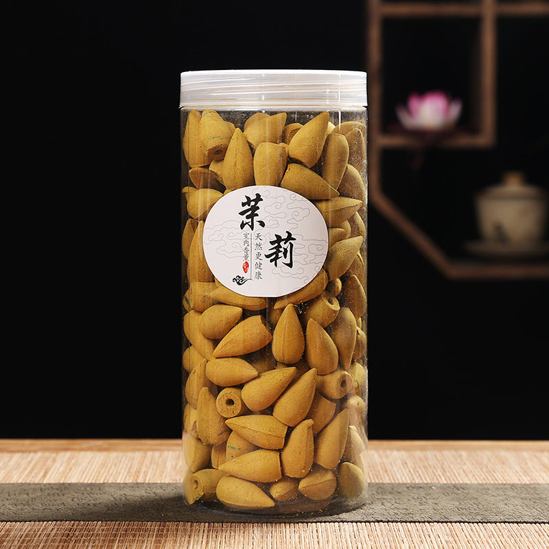 Clear jar filled with cones on a wooden surface with a blurred background