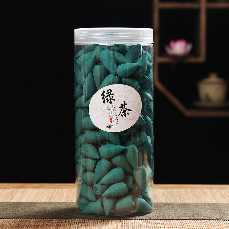 Clear jar filled with green tea cones on a wooden surface with a blurred background
