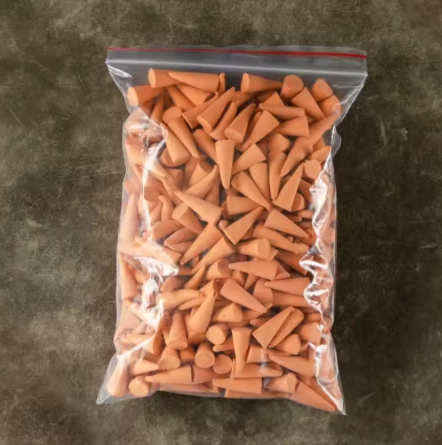 Clear plastic bag filled with terracotta-colored decorative cones on a dark surface