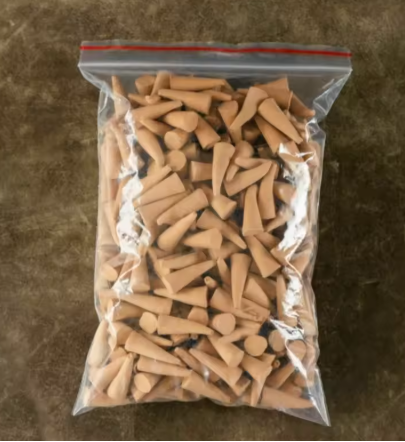 Clear plastic bag filled with wooden golf tees on a brown surface