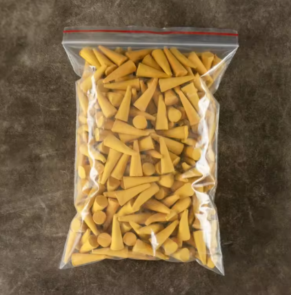 Clear plastic bag filled with yellow golf tees on a brown surface