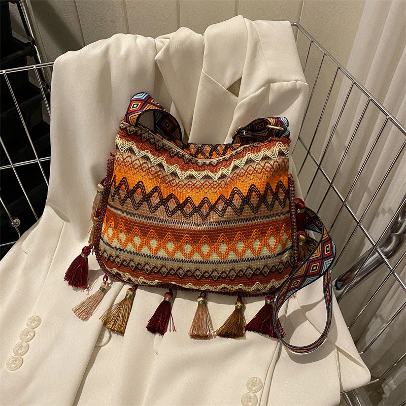 Colorful patterned handbag with tassels on a white coat in a shopping cart.