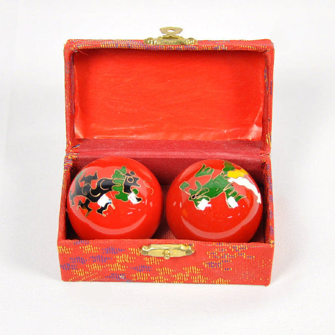 Two red balls with frog designs in an open red box on a white background