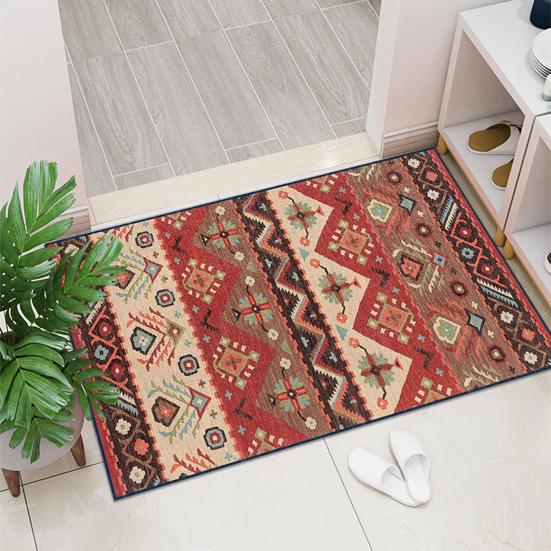 Decorative rug with geometric pattern on a tiled floor next to a plant and white shoes.