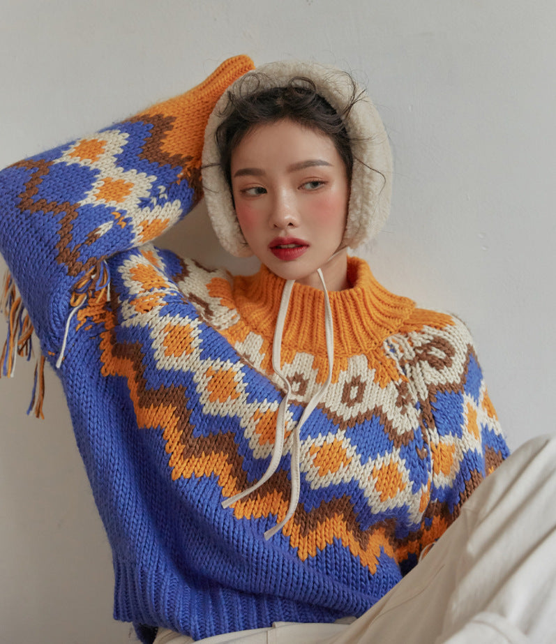 Person wearing a colorful patterned sweater with a hood against a plain background