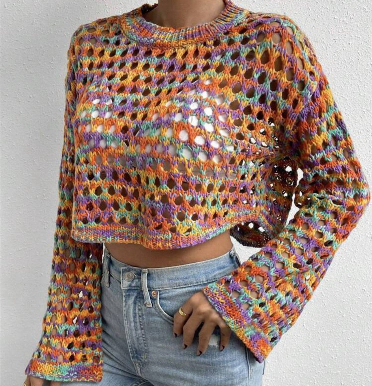 Multicolored crochet sweater worn by a person on a plain background