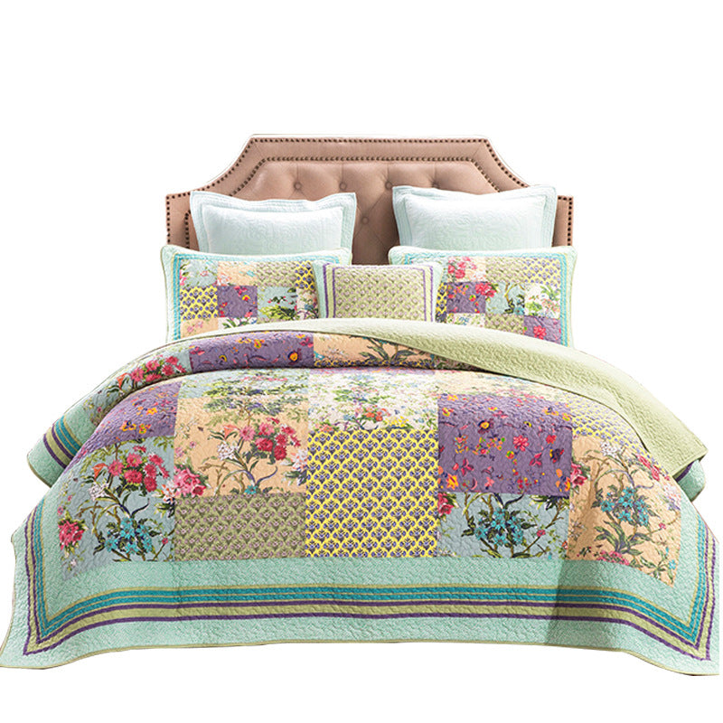 Colorful patchwork quilt with floral patterns on a bed with white pillows.
