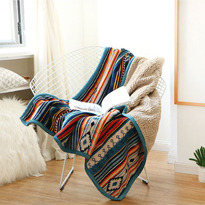 Colorful patterned blanket draped over a chair in a room with a window and plant.