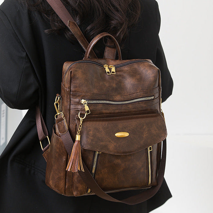 Brown leather backpack worn by a person on a white background
