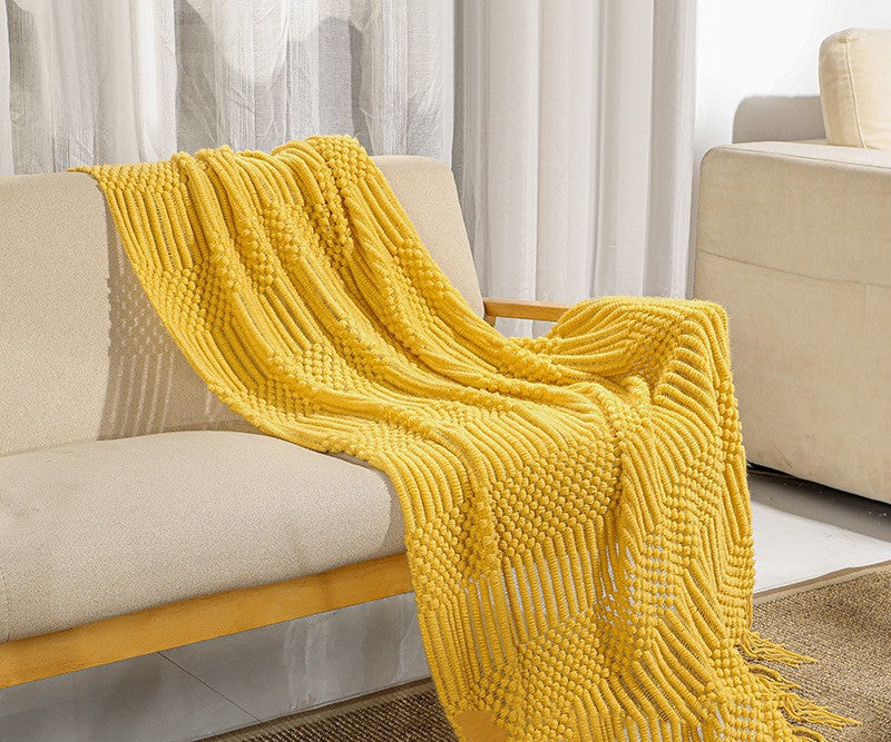 Yellow textured blanket draped over a beige armchair in a living room setting.