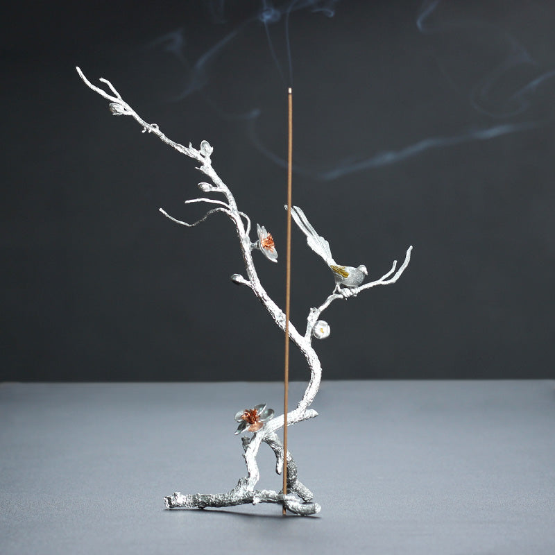 Decorative incense holder with branches and birds on a dark background