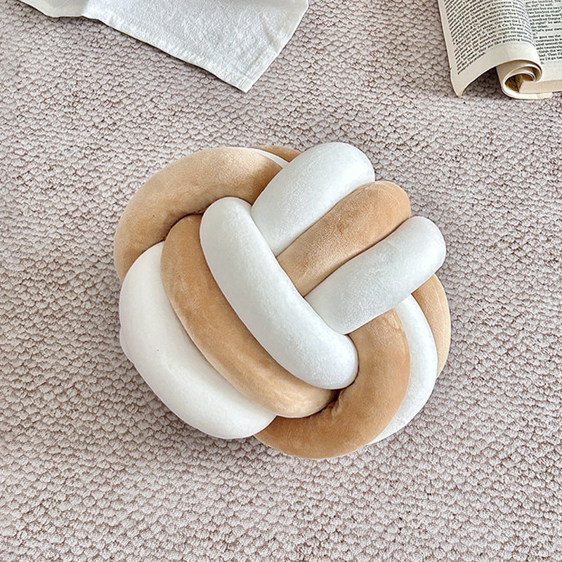 Decorative knot toy with wooden and white elements on a textured surface