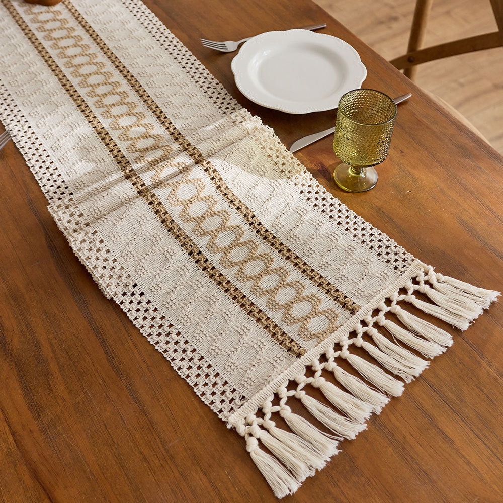 Decorative table runner with tassels on a wooden table.