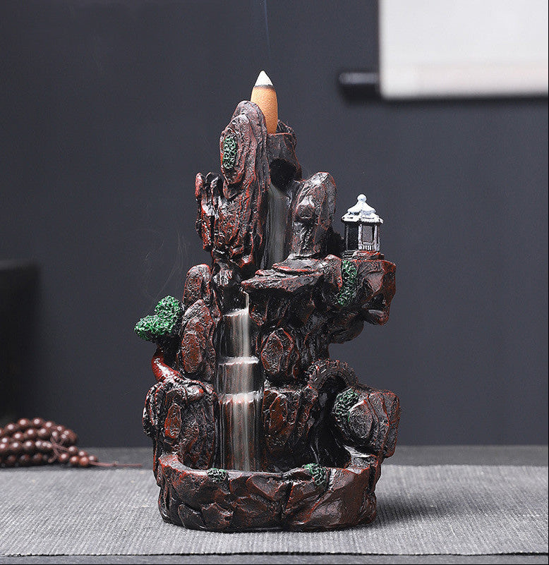 Decorative water fountain with rocks and a candle on a dark background