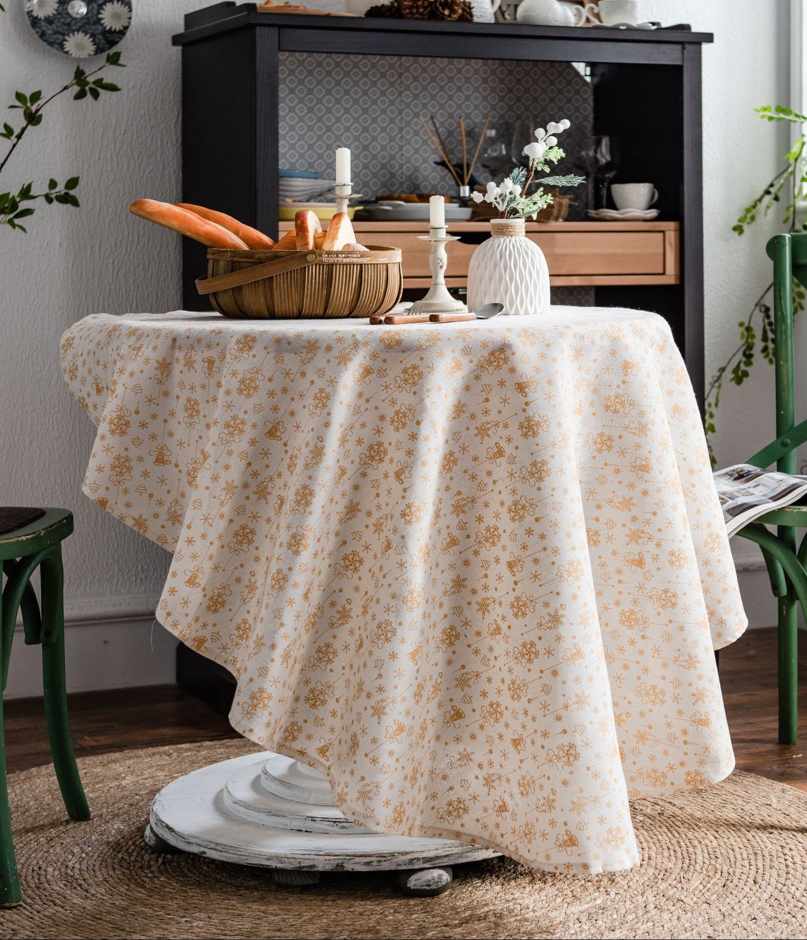 Dining room with a floral tablecloth on a round table, green chairs, and a black cabinet.