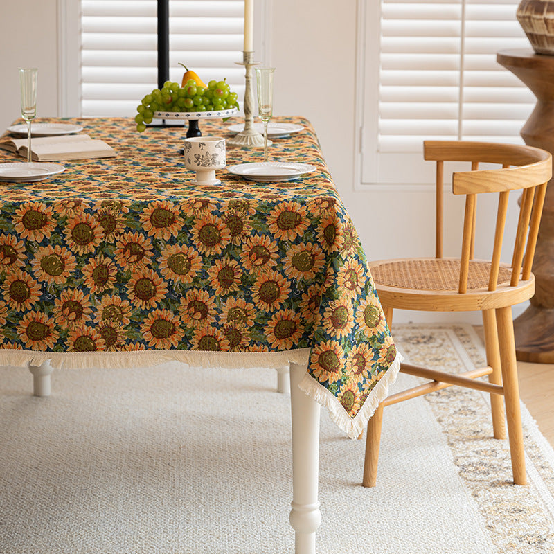 Dining room with a table covered by a sunflower-patterned tablecloth.