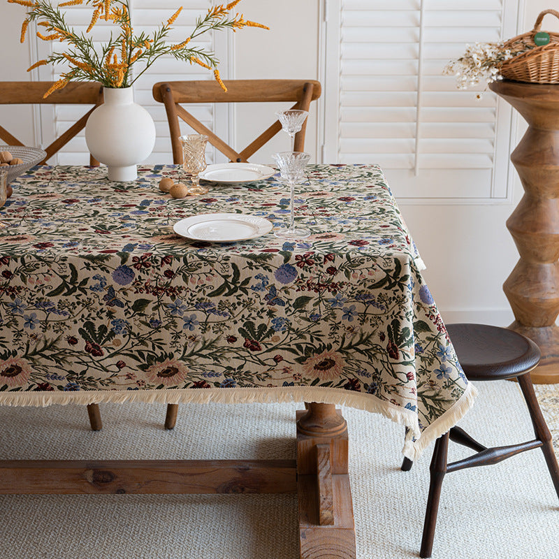Dining table with a floral tablecloth, chairs, and decorative elements in a room.
