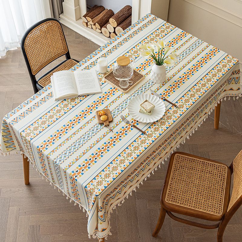 Dining table with a patterned tablecloth, books, and decorative items in a room.