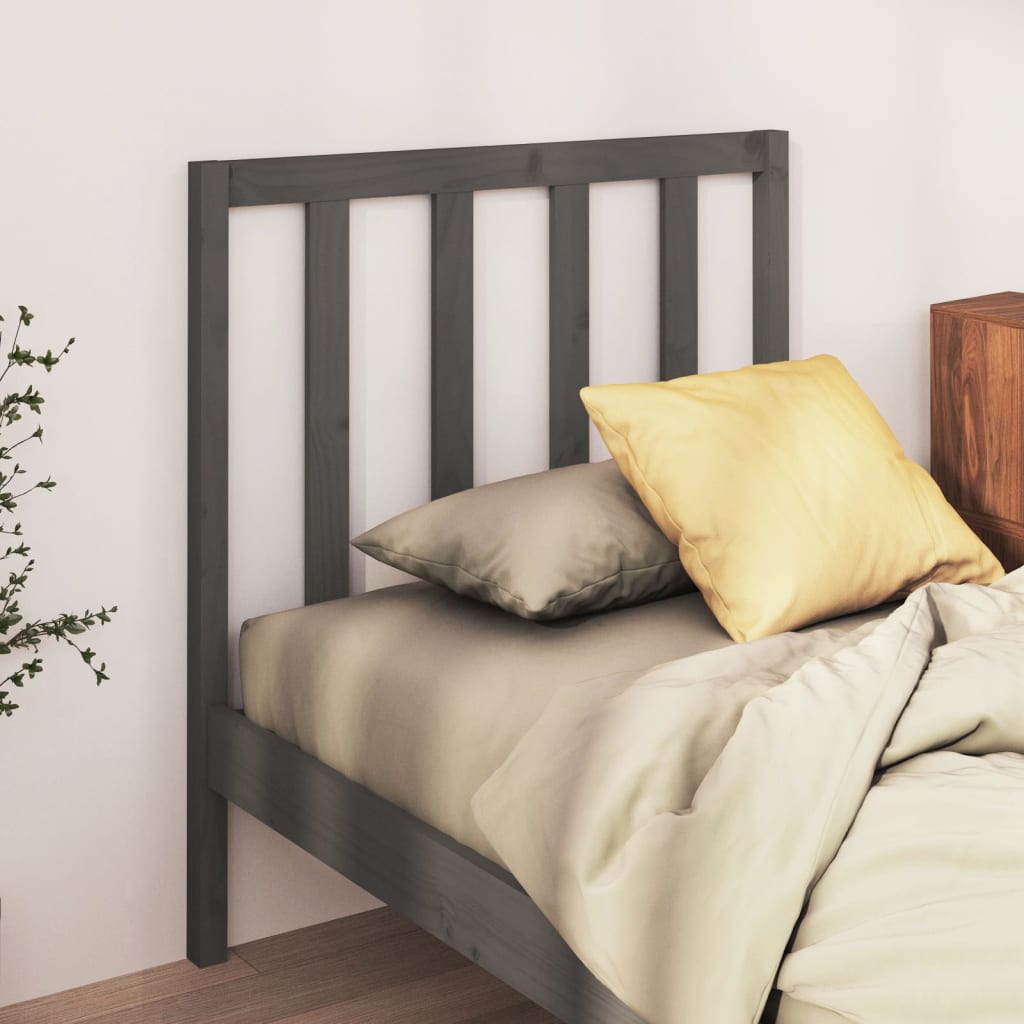 Bed with gray headboard and pillows against a white wall