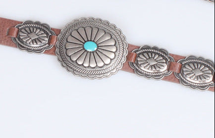 Belt with silver concho design and turquoise stones on a white background