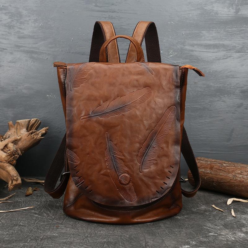 Brown leather backpack with feather design on a gray surface