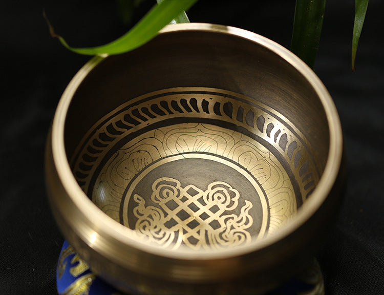 Brass bowl with intricate designs on a dark background