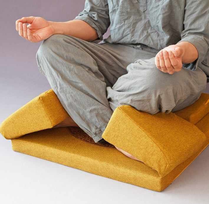 Person sitting on a yellow footstool with a plain background