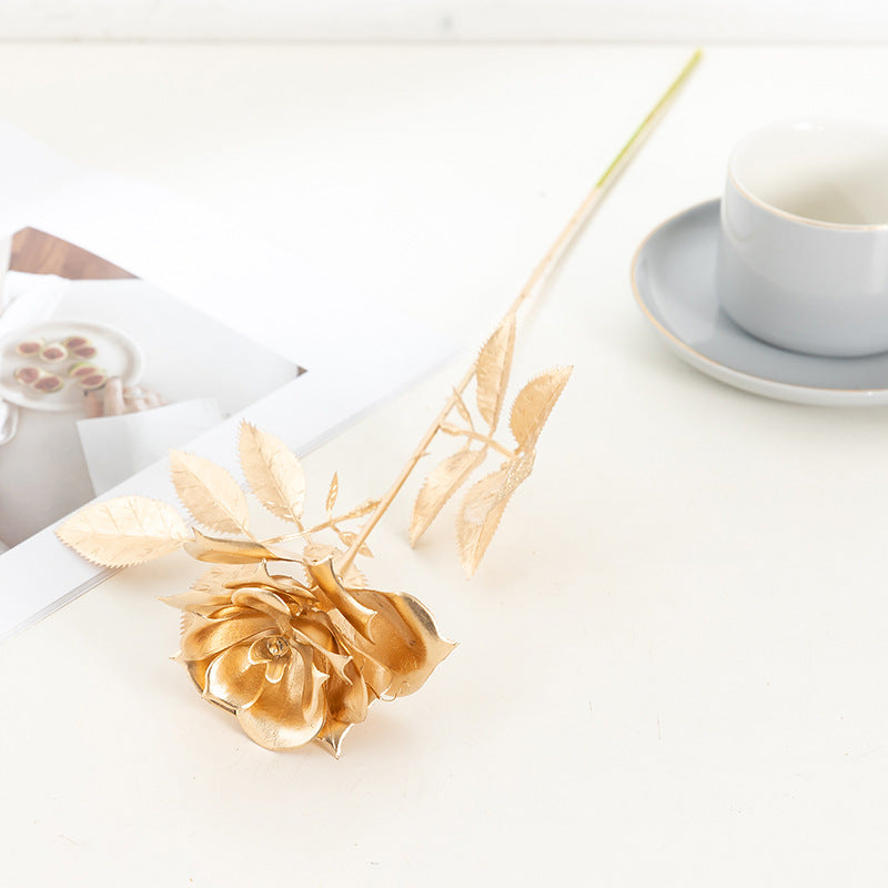 Gold flower on a white surface with a cup and saucer in the background