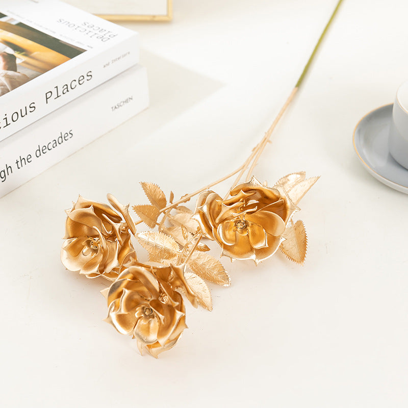 Gold floral decorations on a white surface with a book and cup in the background