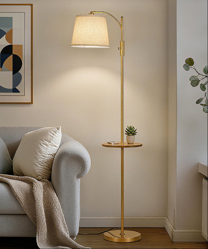 Gold floor lamp in a living room with a sofa and abstract art on the wall.