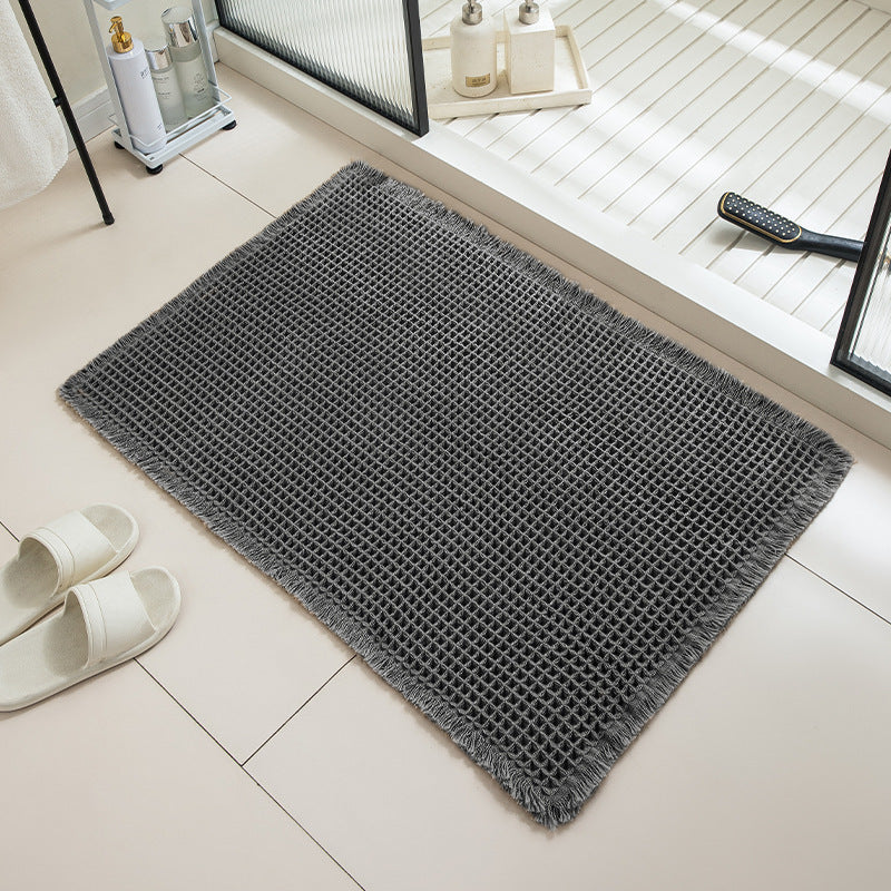Gray doormat on a tiled floor with white slippers nearby