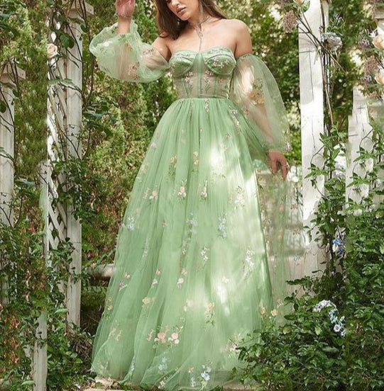 Woman in a green floral dress standing in a garden setting