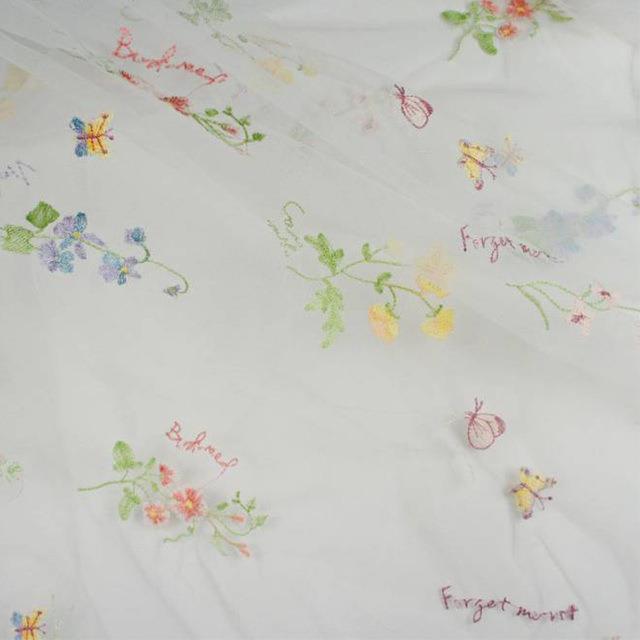 Embroidered fabric with floral patterns and text on a white background