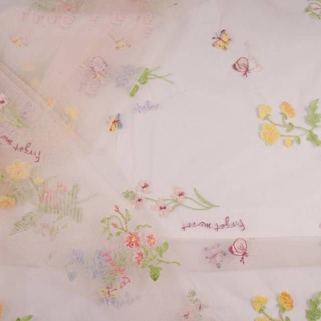 Embroidered fabric with floral patterns and text on a light background