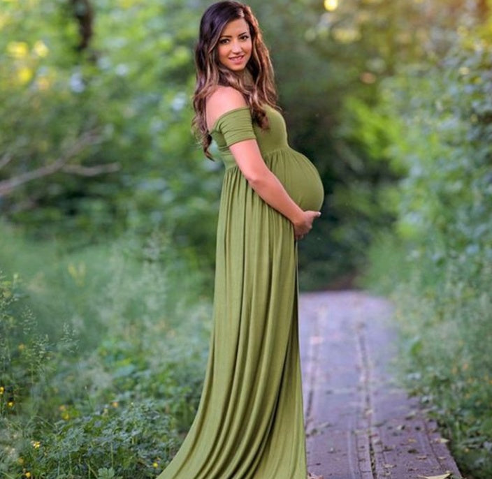 Pregnant woman in a green dress standing in a natural setting