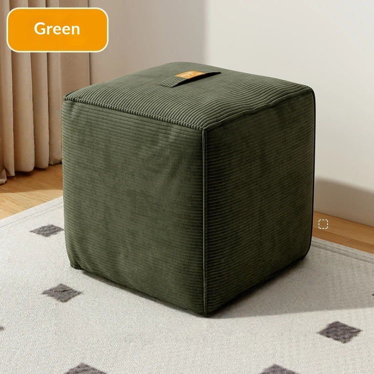 Green cube-shaped ottoman on a patterned rug with a neutral background