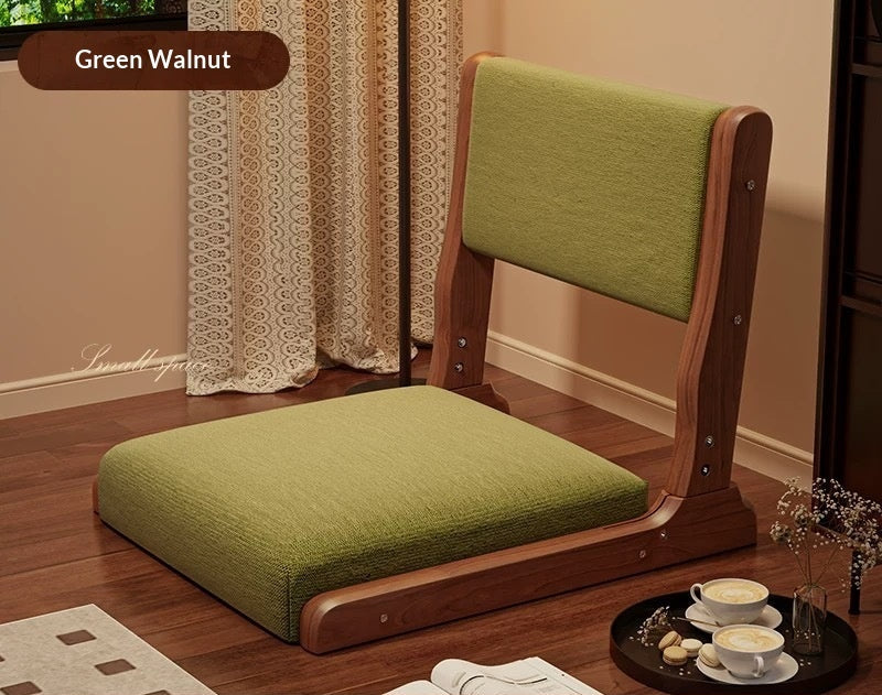 Green cushioned chair with wooden frame on a wooden floor, surrounded by tea set and decorative items.