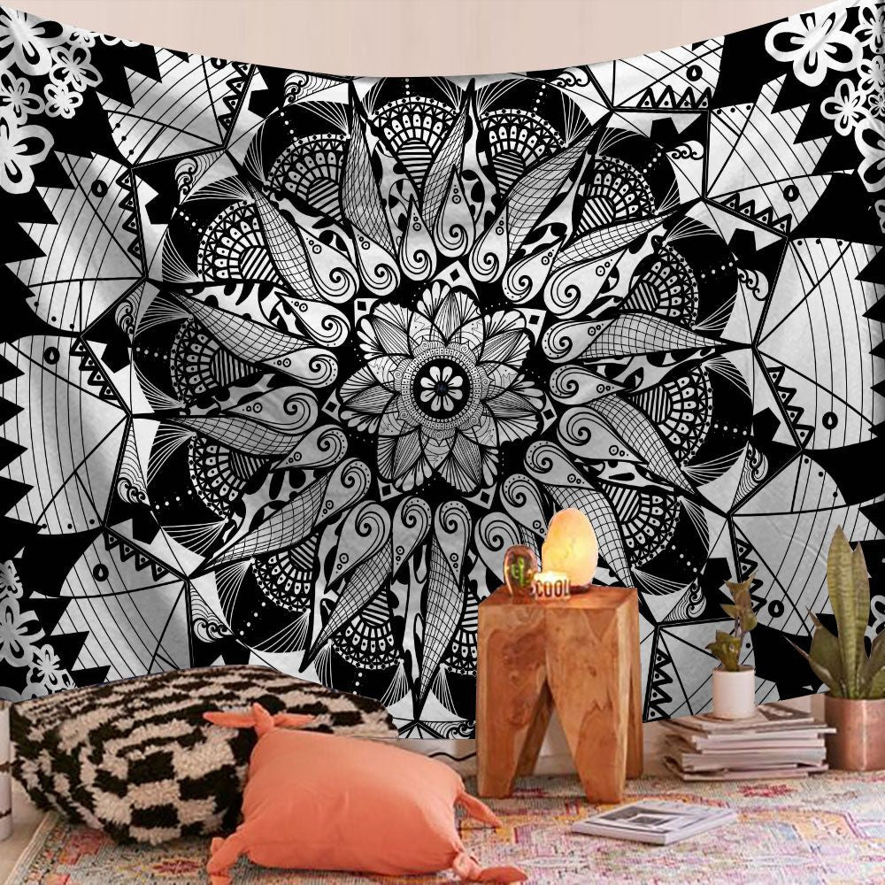Black and white geometric tapestry with a decorative pillow and plant in a room.