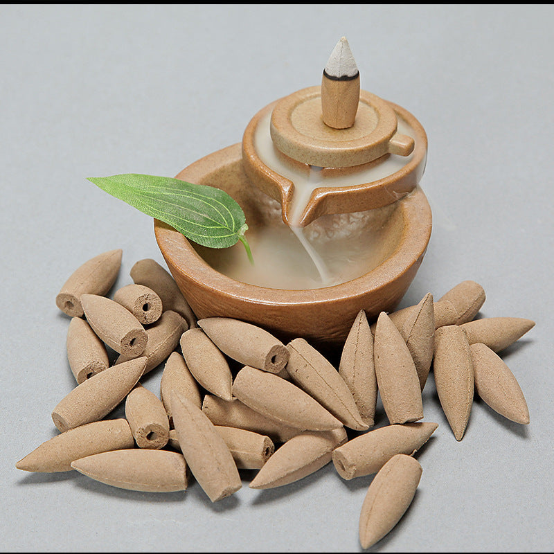 Incense burner with cones and a leaf on a gray background