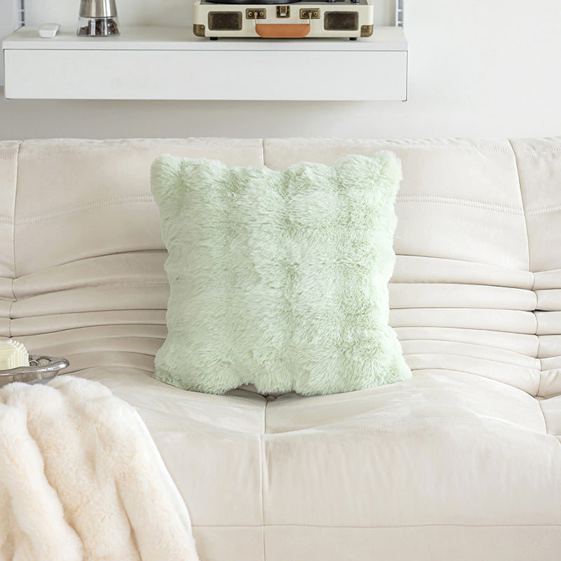 Light green textured pillow on a white couch with a neutral background